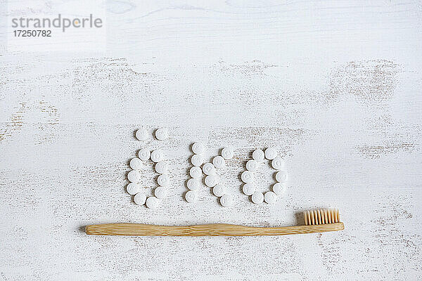 Bamboo Material Zahnbürste mit Zahnpasta Pille auf strukturierten Hintergrund