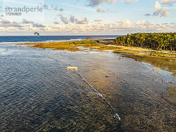 Drohnenansicht der Küstenlinie der Insel Siargao mit einem einsamen Kitesurfer im Hintergrund