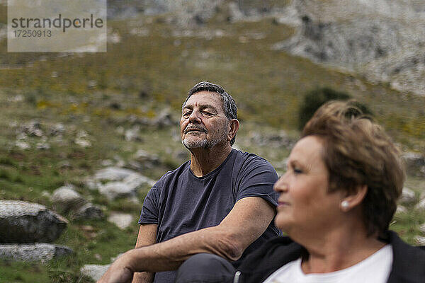 Ältere Frau mit einem Mann im Hintergrund  der eine Pause in den Bergen macht