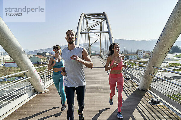 Multiethnische gesundheitsbewusste Freunde laufen auf der Brücke