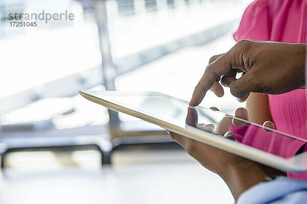 Männlicher Unternehmer  der ein digitales Tablet von einer Kollegin im Büro benutzt