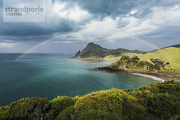 Der Regenbogen wölbt sich gegen die Gewitterwolken  die sich über der Küste der Coromandel-Halbinsel sammeln