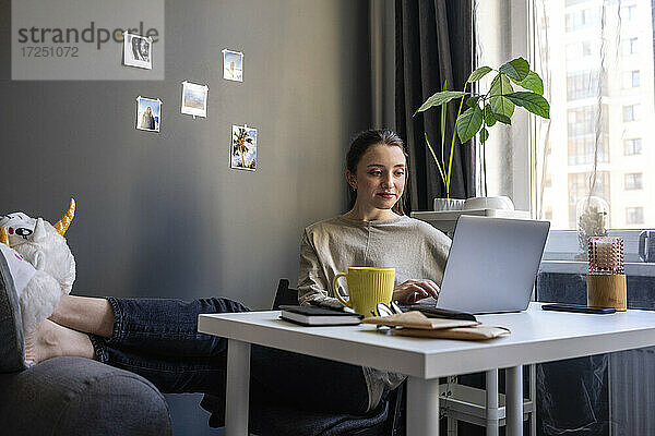 Junge Frau arbeitet zu Hause am Laptop