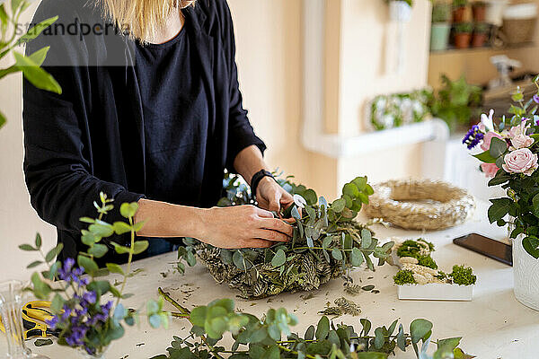 Eine Floristin fertigt in einem Workshop ein Blumenarrangement aus Blättern an