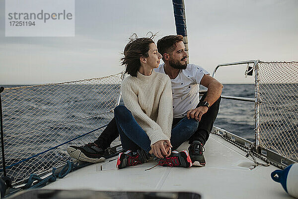 Freundin und Freund sitzen auf einem Segelboot im Urlaub