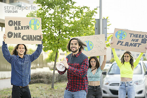 Lächelnder männlicher Aktivist  der auf einer Straße in der Stadt gegen den Klimawandel protestiert