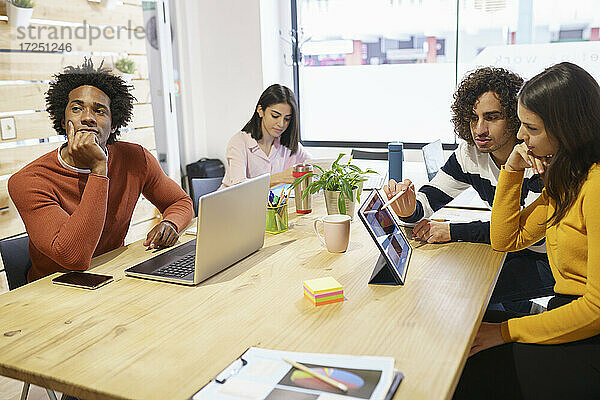 Geschäftsleute diskutieren über ein digitales Tablet am Konferenztisch im Büro