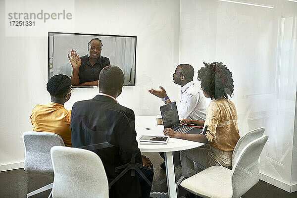 Männliche und weibliche Fachleute diskutieren während einer Videokonferenz im Coworking-Büro