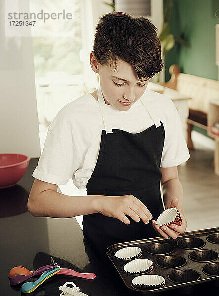 Junge bereitet Muffinblech in der Küche zu Hause vor