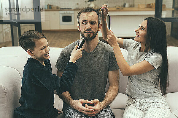 Familie schneidet einem Mann zu Hause die Haare