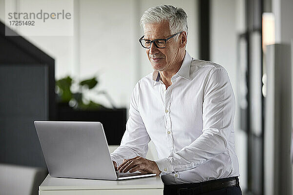 Männlicher Unternehmer mit Laptop bei der Arbeit im Büro