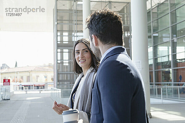 Unternehmerin lächelt  während sie einen männlichen Kollegen ansieht