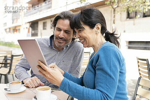 Ehepaar  das auf der Terrasse sitzend ein digitales Tablet benutzt