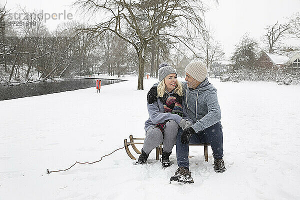 Ehepaar sitzt im Winter auf einem Schlitten
