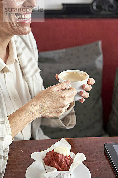 Lächelnde Frau trinkt Kaffee in der Cafeteria