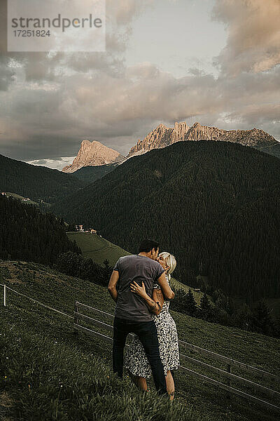 Paar  das sich umarmt  während es im Gras in der Nähe der Dolomitengebirge in Südtirol  Italien  steht