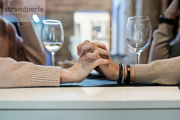 Ehepaar mit verschränkten Händen im Restaurant sitzend