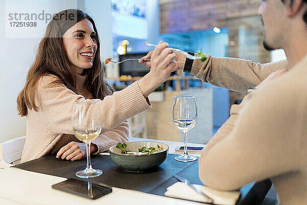 Ehepaar füttert sich gegenseitig mit Salat am Restauranttisch