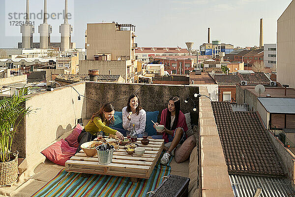 Weibliche Freunde genießen beim Essen auf der Terrasse