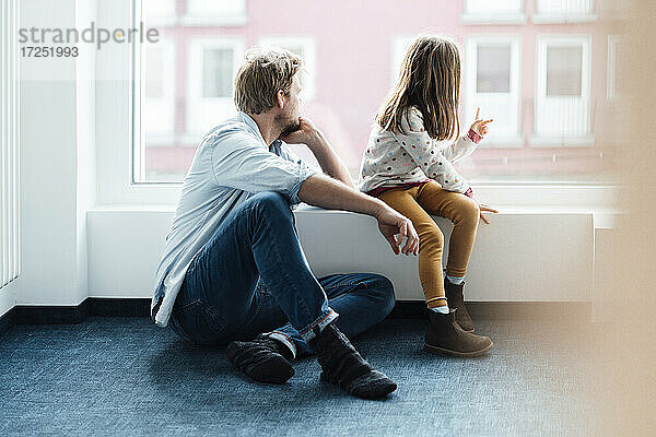 Vater und Tochter schauen durch das Fenster zu Hause
