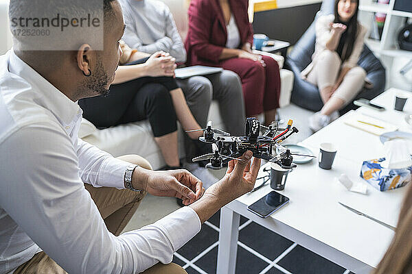 Afrikanischer männlicher Ingenieur  der mit Kollegen während einer Besprechung in einem Coworking-Büro über eine Drohne diskutiert