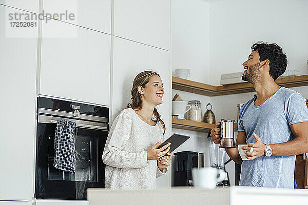 Fröhliches junges Paar  das sich in der häuslichen Küche stehend ansieht