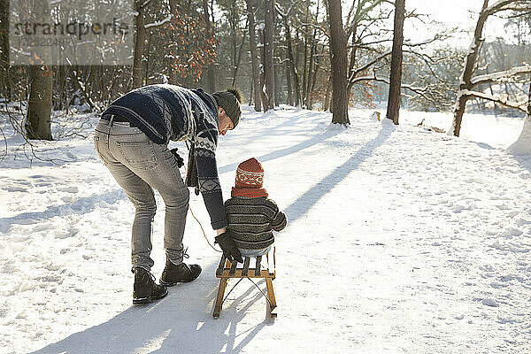 Vater bringt seinem Sohn das Schlittenfahren im Schnee bei