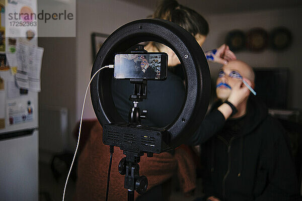 Maskenbildnerin mit Modell beim Vlogging im Studio