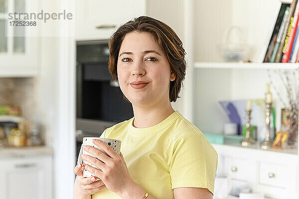 Schöne Frau mit kurzen Haaren hält Kaffeetasse zu Hause