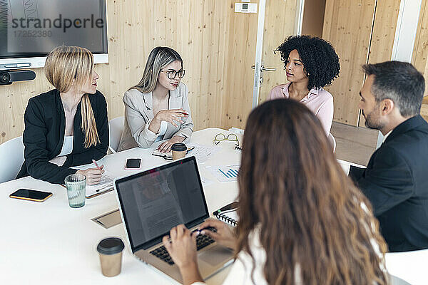 Männliche und weibliche Mitarbeiter diskutieren während einer Besprechung im Büro