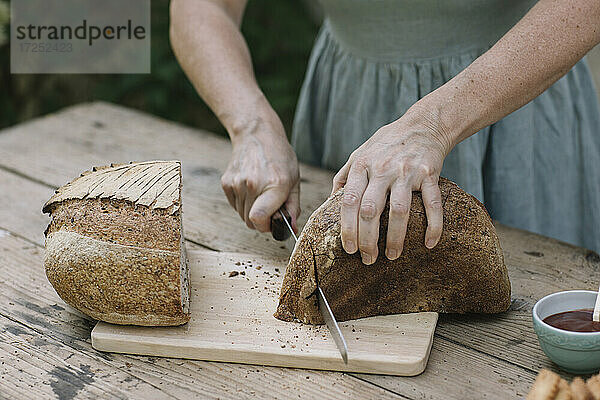 Reife Frau schneidet Brot auf dem Tisch