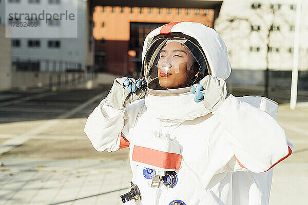 Weibliche Astronautin mit Helm  während sie an einem sonnigen Tag im Freien steht
