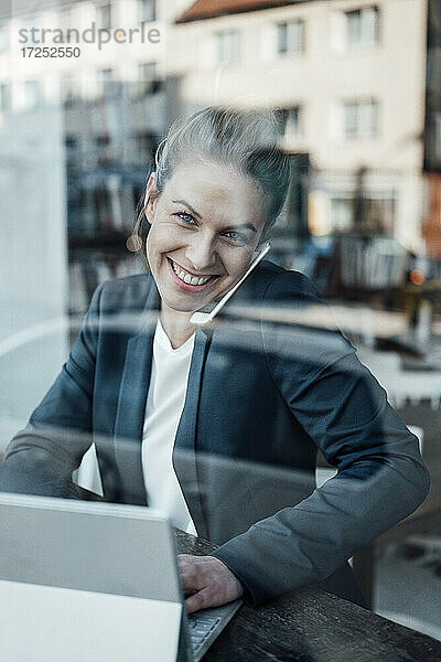 Geschäftsfrau mit digitalem Tablet  die in einem Café mit einem Mobiltelefon spricht