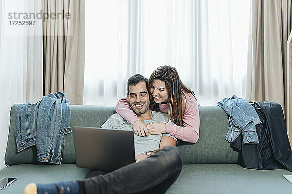 Lächelndes erwachsenes Paar  das im Hotel auf einen Laptop schaut