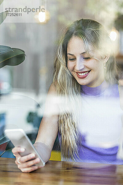 Lächelnde Frau mit Smartphone im Restaurant