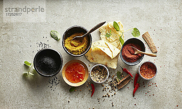 Studioaufnahme von Naan-Brot  Chili-Dip-Sauce und Schalen mit verschiedenen Masala-Gewürzen