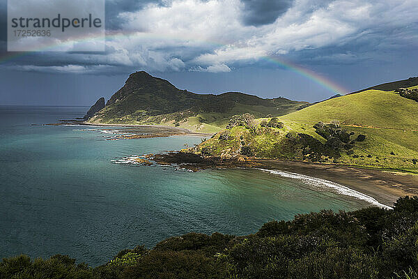 Der Regenbogen wölbt sich gegen die Gewitterwolken  die sich über der Küste der Coromandel-Halbinsel sammeln