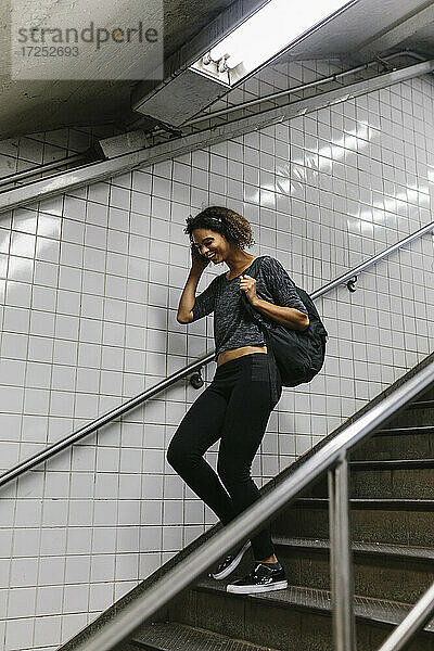 Junge Frau mit Kopf in der Hand  die auf einer Treppe in der U-Bahn nach unten geht