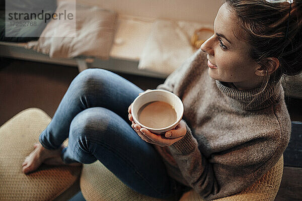 Nachdenkliche Frau hält eine Kaffeeschale  während sie in einem Café sitzt