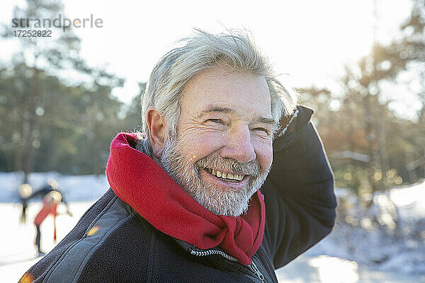 Glücklicher älterer Mann mit rotem Schal im Winter