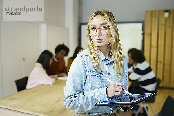 Blonde schöne Geschäftsfrau hält digitale Tablette im Büro