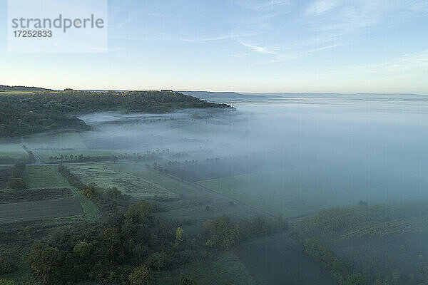 Drohnenansicht der in dichten Nebel gehüllten Landschaft in der Morgendämmerung