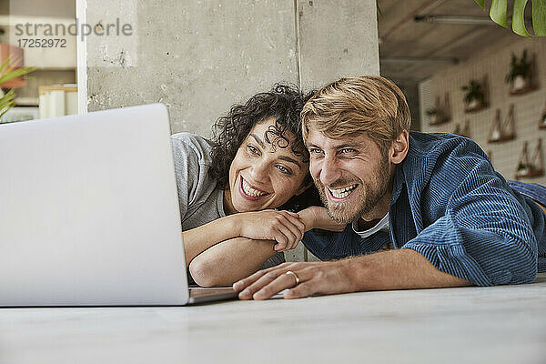 Glückliches Paar  das gemeinsam den Laptop in seiner Wohnung betrachtet