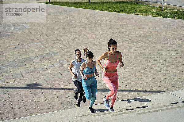 Multi-ethnische männliche und weibliche Freunde joggen auf Stufen im Park