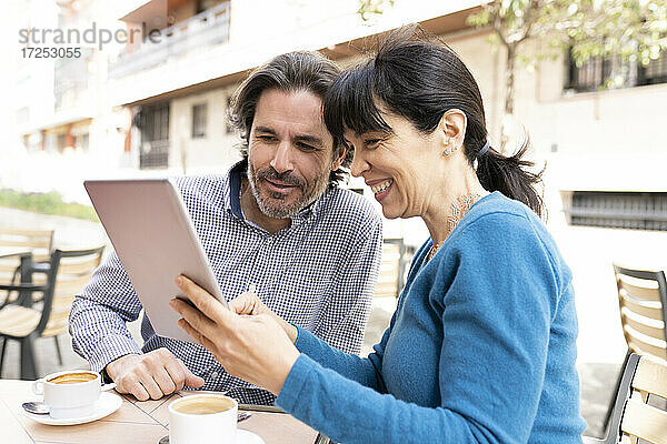 Mann und Frau benutzen ein digitales Tablet auf einer Terrasse