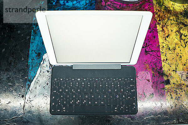 Digitales Tablet mit Tastatur auf rauem Tisch in einer Fabrik