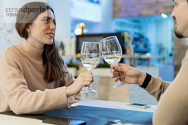 Freund und Freundin stoßen mit Gläsern an und schauen sich im Restaurant an