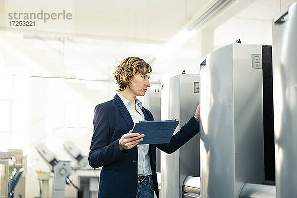 Weiblicher Manager mit digitalem Tablet zur Überprüfung einer Maschine in einer Fabrik
