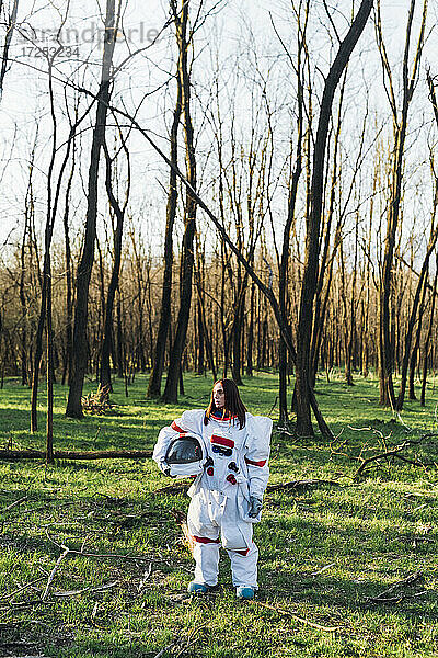 Astronautin mit Weltraumhelm im Wald stehend
