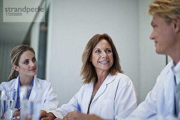 Weibliche Ärzte lächeln ihren männlichen Kollegen im Krankenhaus an